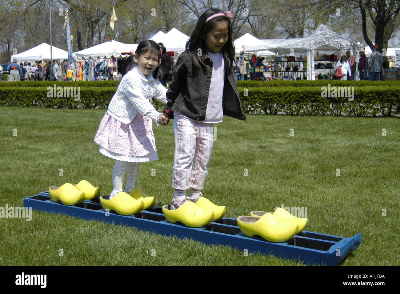 Deux filles de l'école d'Asie / sœurs sur les curseurs de sabots de bois pendant le Festival des tulipes en Hollande, Michigan USA Banque D'Images