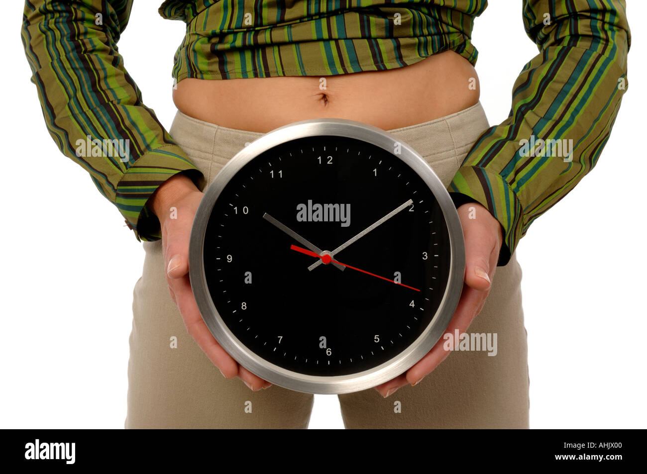Femme tenant une horloge en face de l'estomac Banque D'Images