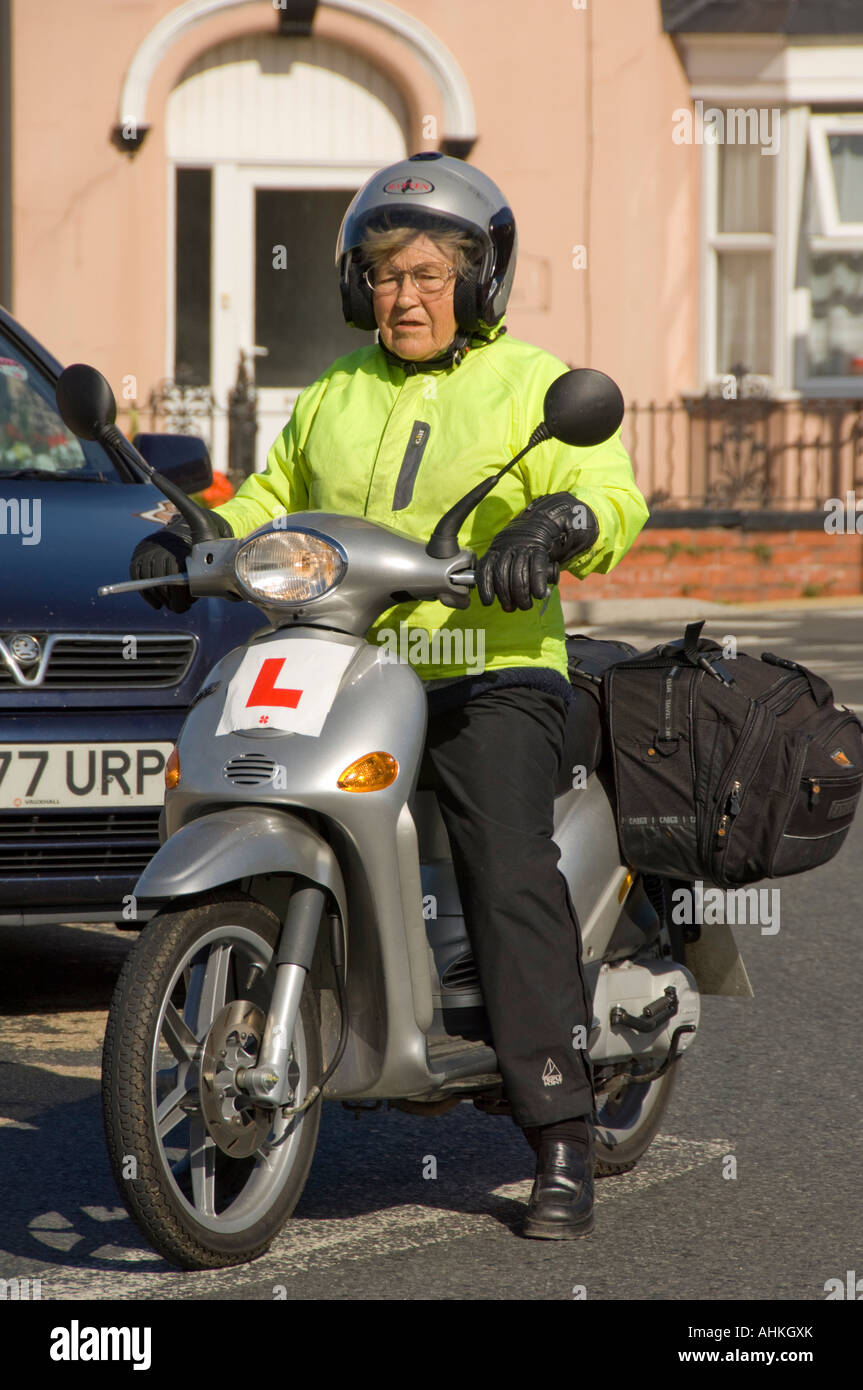 Femme âgée à apprendre à faire du vélo moto scooter à Aberystwyth Wales UK  - le port du casque et gilet jaune, plaques L Photo Stock - Alamy