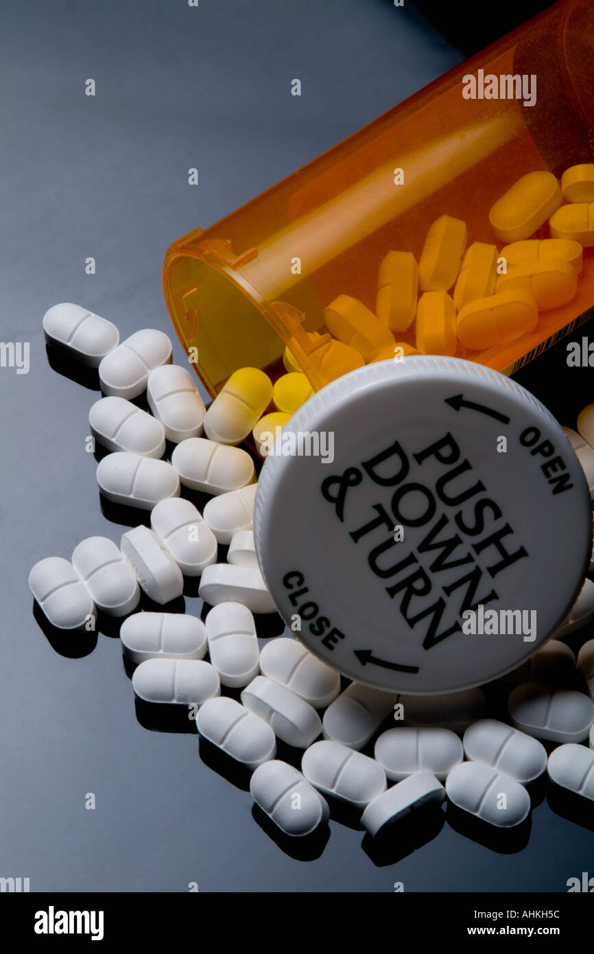 Pilules blanches et bouteille de pilules en plastique sur fond noir Banque D'Images