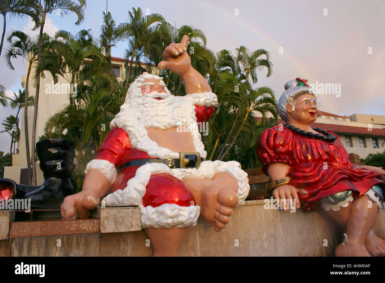 Père Noël hawaïen et Mme Claus au sommet d'une fontaine à Honolulu Hawaii rainbow en arrière-plan Banque D'Images