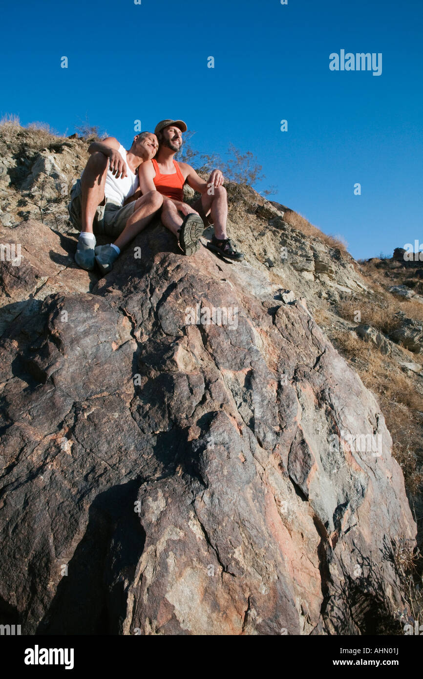 Gay couple sitting on boulder Banque D'Images