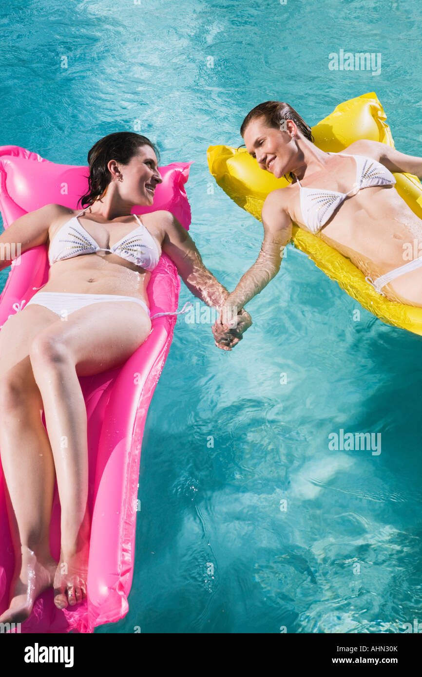 Couple de lesbiennes sur des radeaux de détente en piscine Banque D'Images