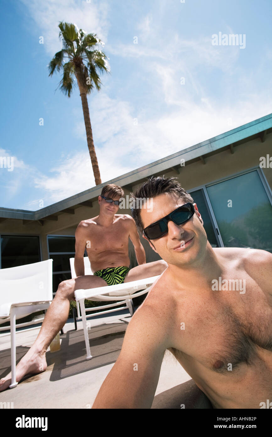 Gay couple relaxing by swimming pool Banque D'Images