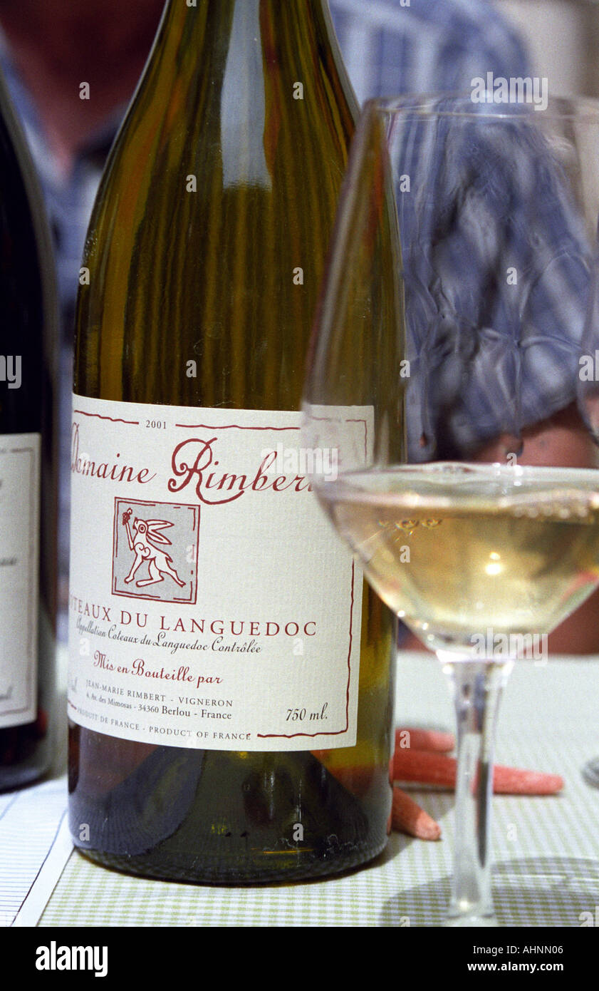Une bouteille et un verre de Domaine Rimbert, administré par le vigneron Jean-Marie Rimbert qui est assis à l'arrière-plan, Saint-Chinian, Coteaux du Languedoc, Languedoc-Roussillon, France Banque D'Images