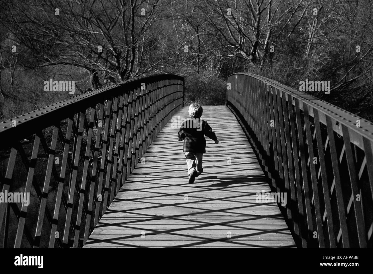 Garçon courir sur bridge noir et blanc Banque D'Images