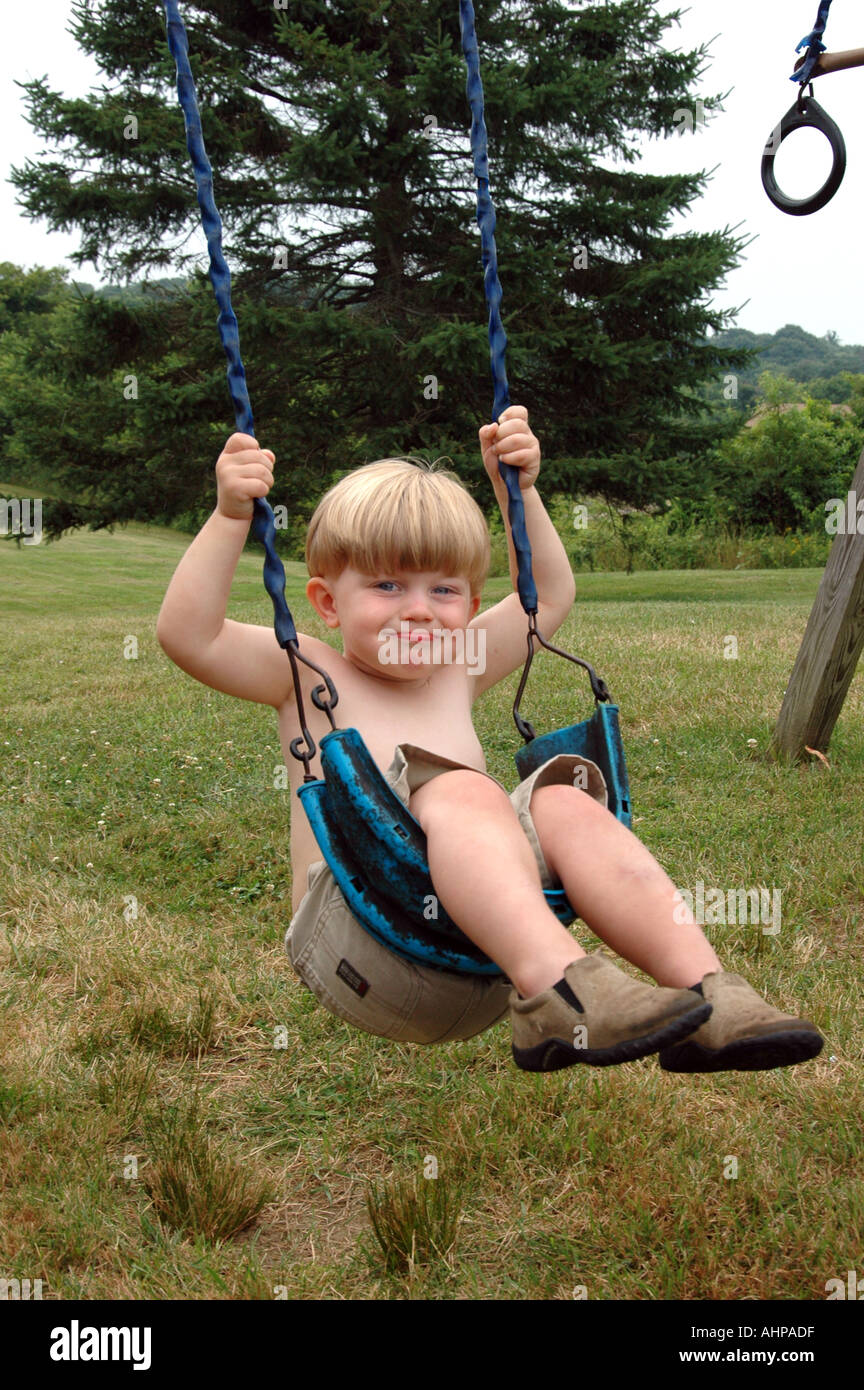 Enfant jouant petit garçon ça balance on swing Banque D'Images