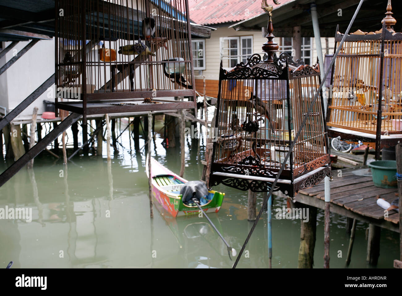 Les cages à oiseaux pendre hors des maisons construites sur pilotis dans la mer dans le golfe de Thaïlande Banque D'Images