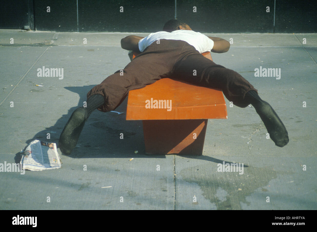 L'homme noir sans-abri dormant sur un banc de parc New York New York Banque D'Images