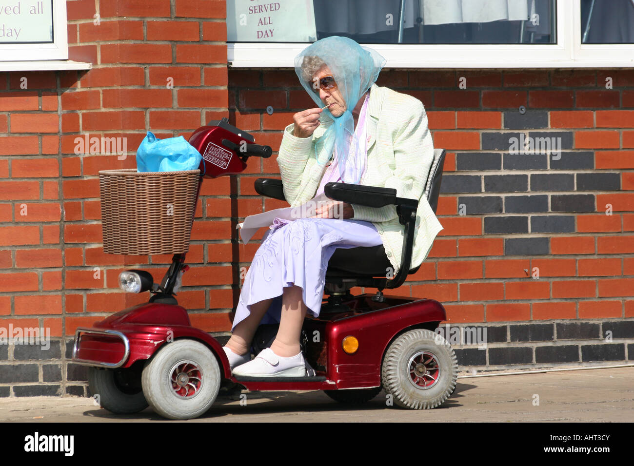 Vieille dame sur buggy motorisé ou fauteuil de manger du poisson et frites. Banque D'Images