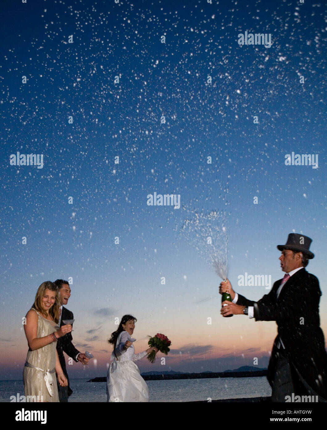 La pulvérisation d'ouverture homme bouteille de champagne plus de fête de mariage sur la plage, Coucher de soleil Banque D'Images