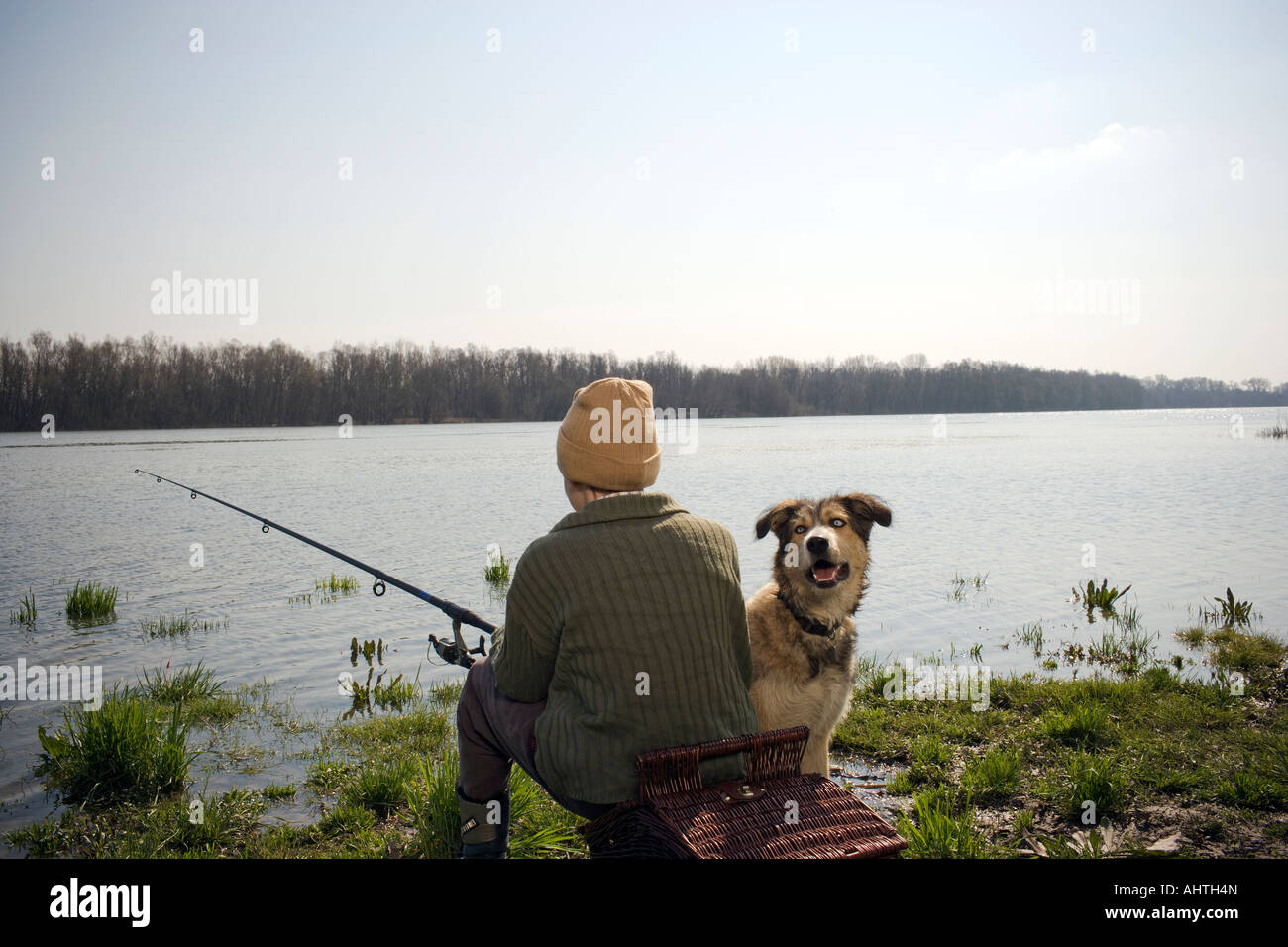 Boy (12-14) la pêche en rivière avec chien de compagnie, vue arrière Banque D'Images