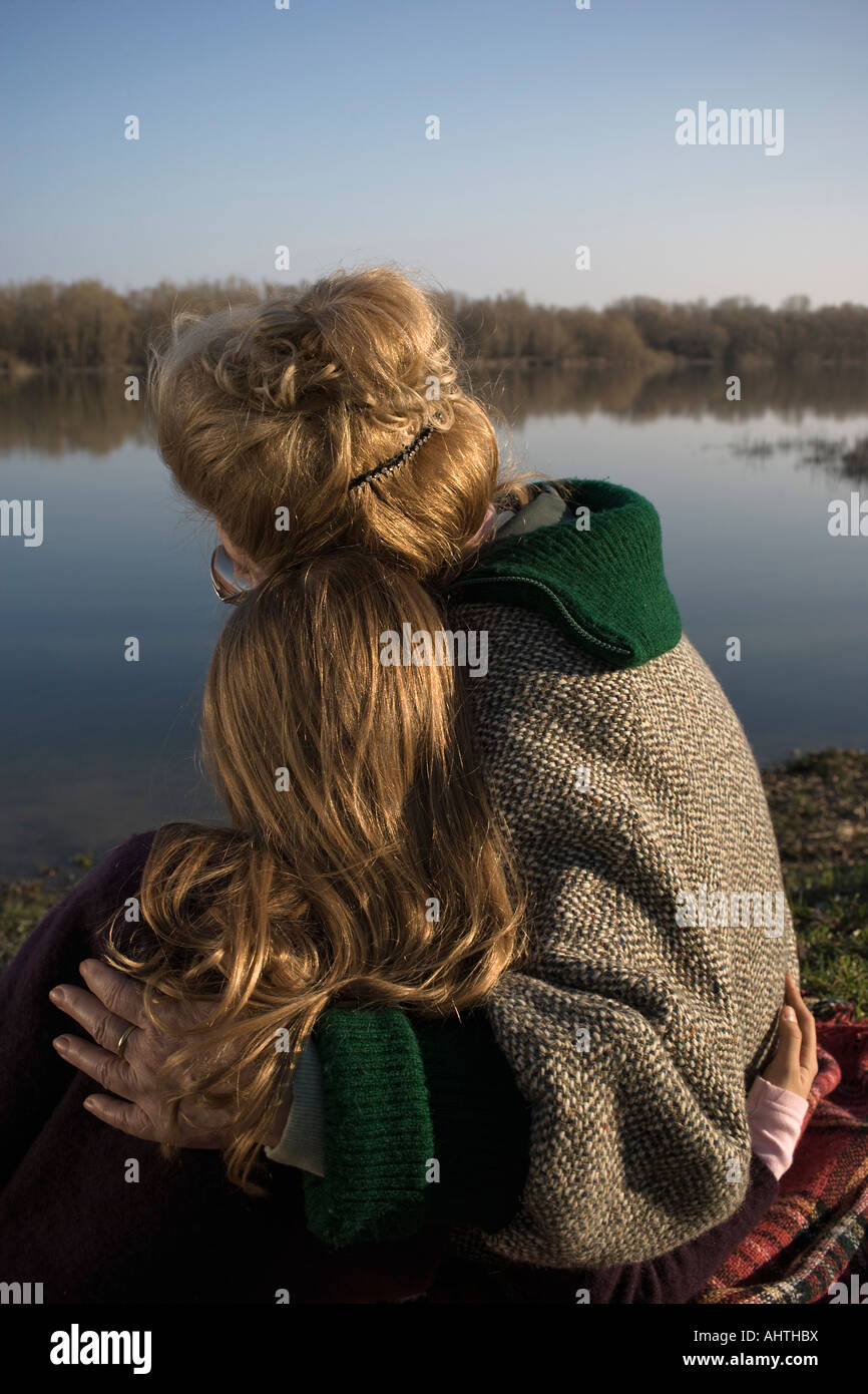 Grand-mère et petite-fille (10-12) sitting by river, vue arrière Banque D'Images