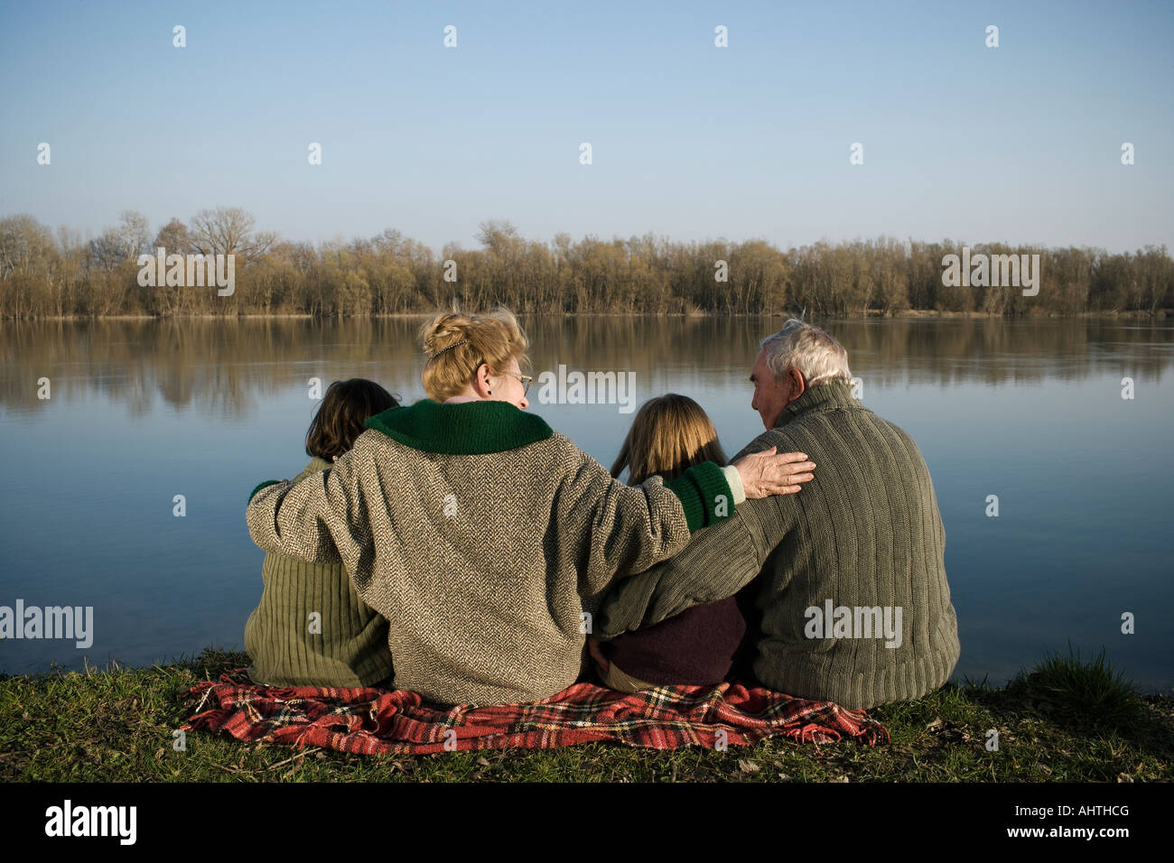 Les grands-parents, petit-fils (12-14) et petite-fille (10-12) sitting by river, vue arrière Banque D'Images