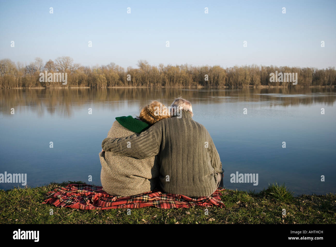 Senior couple sitting on rug par rivière, vue arrière Banque D'Images