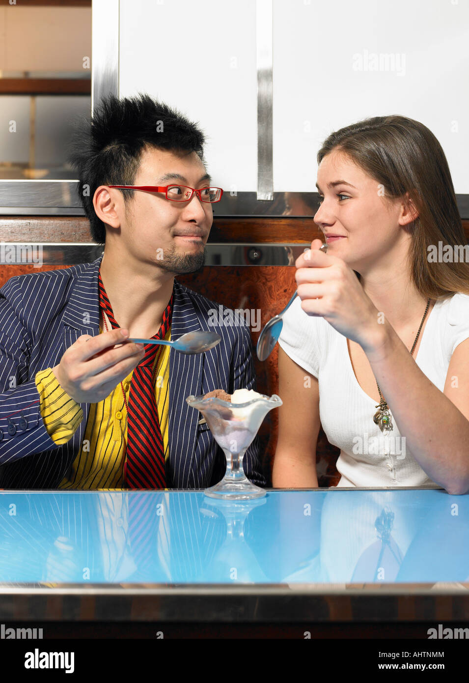 Jeune couple partager icecream dans cafe smiling at each other Banque D'Images