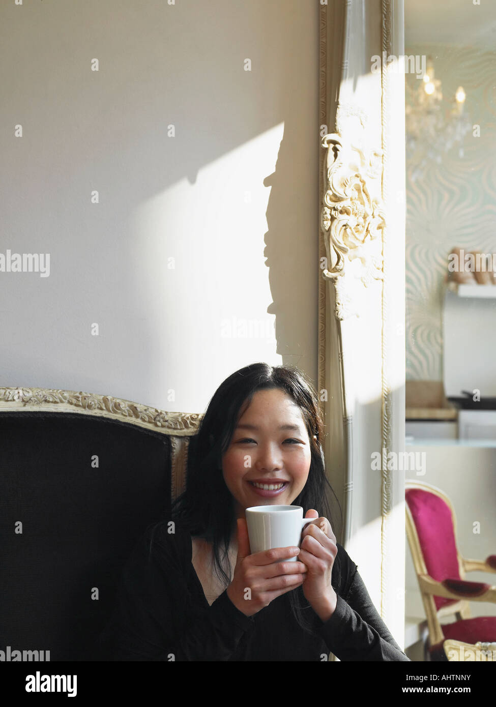Jeune femme assise dans le holding cup, smiling, portrait Banque D'Images