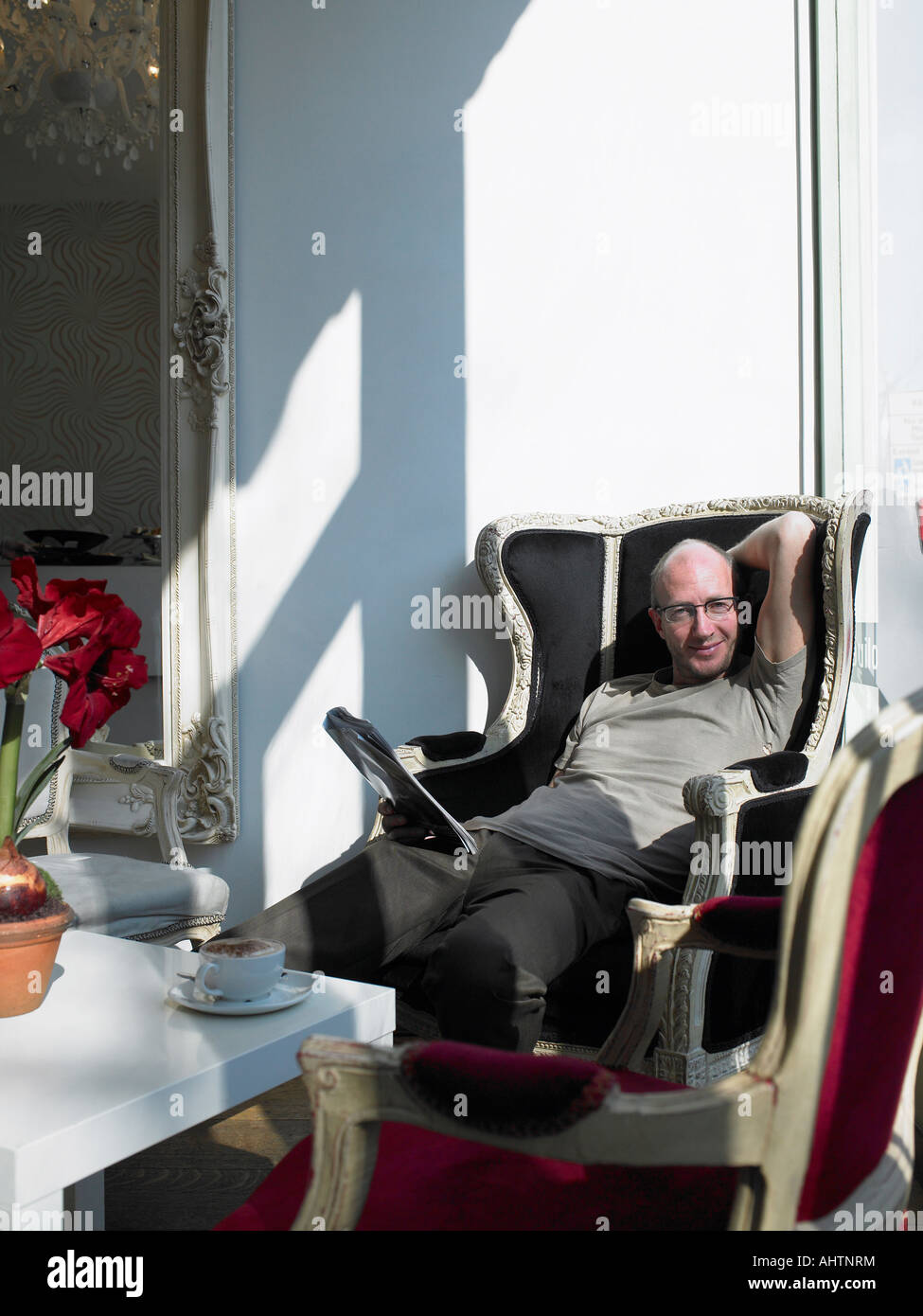 Man relaxing in armchair in cafe, smiling, portrait Banque D'Images