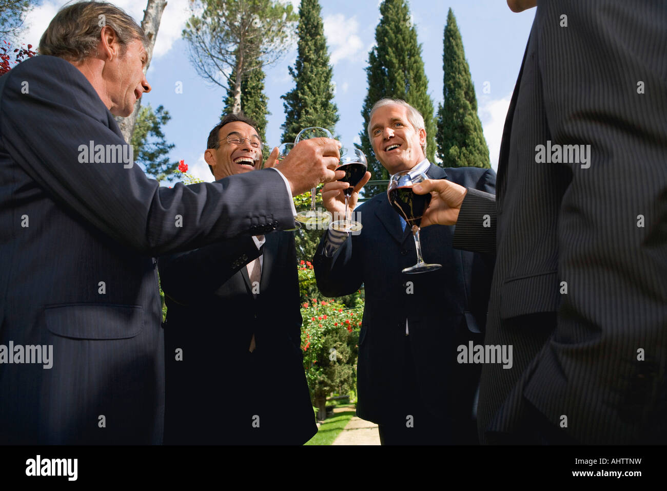 Quatre hommes d'boire du vin dans un jardin Banque D'Images