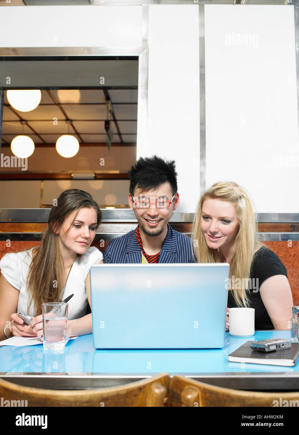 Trois personnes looking at laptop dans un diner Banque D'Images