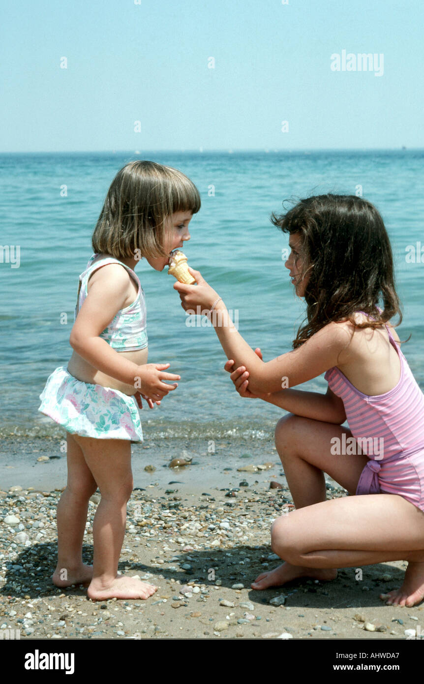 Girl partage ses glaces avec sa petite sœur Banque D'Images