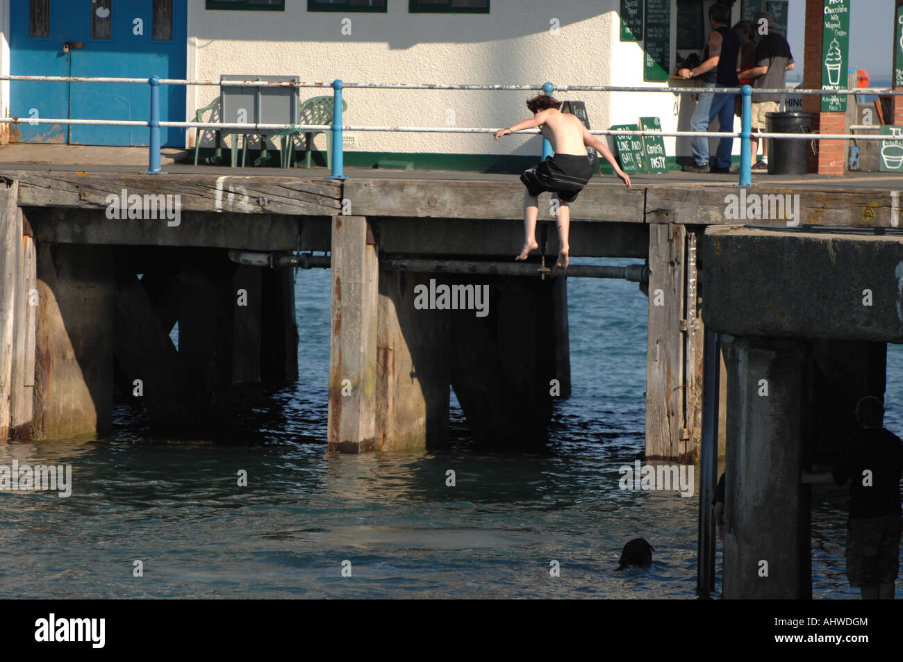 Un garçon bondit dans la mer depuis le mur du port de Weymouth, Dorset, au Royaume-Uni - une folie meurtrière connue sous le nom de "désactivation". Banque D'Images