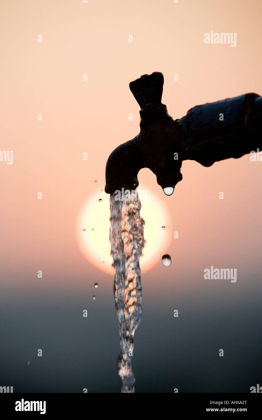 Tuyau de support qui se profile à l'aube du robinet avec de l'eau courante Banque D'Images