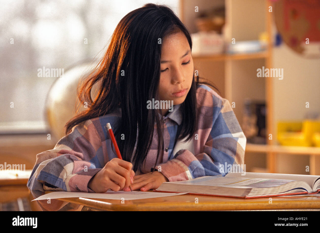 Asian American female student travailler avec manuel à 24 dans l'école moyenne classe Banque D'Images