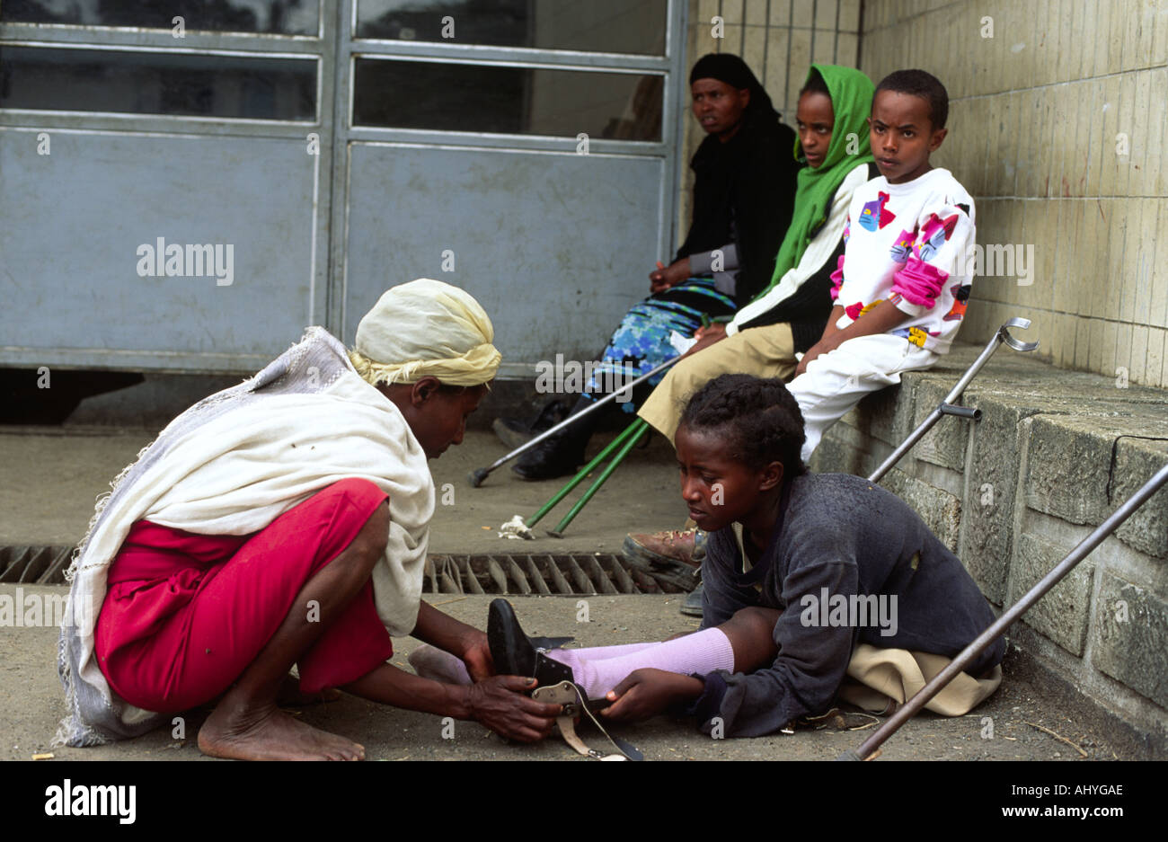 Réglage d'une mère sa fille de neuf étriers, suite à la polio, à l'extérieur de l'hôpital Black Lion, Addis-Abeba, Ethiopie Banque D'Images