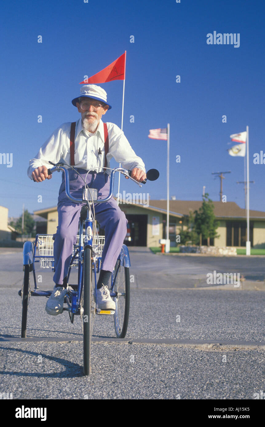 Un vieillard excentrique équitation un tricycle CA Banque D'Images