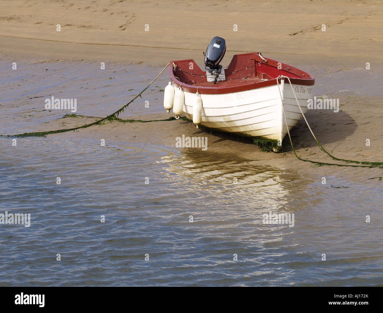 Petit bateau à rames en bois avec un moteur à l'arrière, attaché sur le  bord d'une plage de sable à marée basse Photo Stock - Alamy