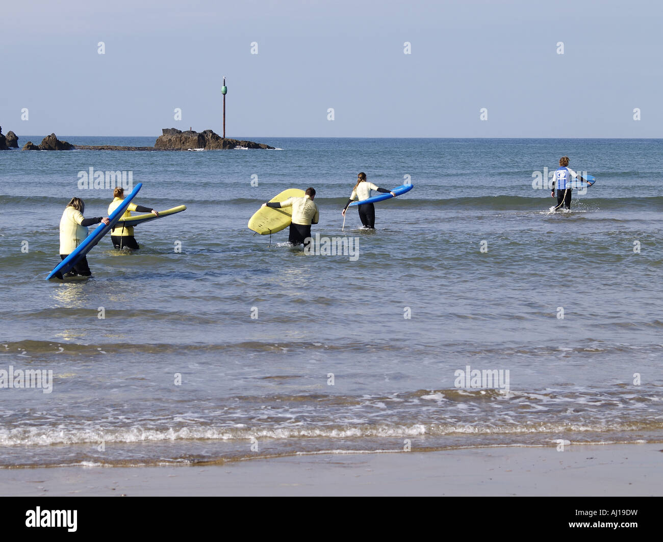 Les surfeurs de l'apprenant dans la mer à pied plage Summerleaze Banque D'Images