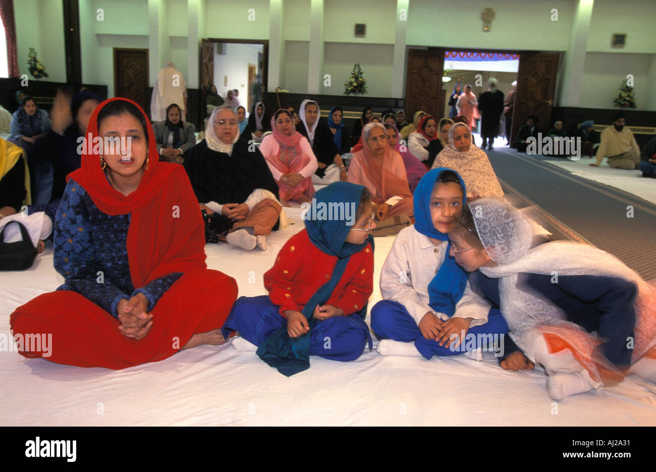 Les femmes sikhes et les enfants en salle de prière au Gurdwara ou temple, Londres, Angleterre. Banque D'Images