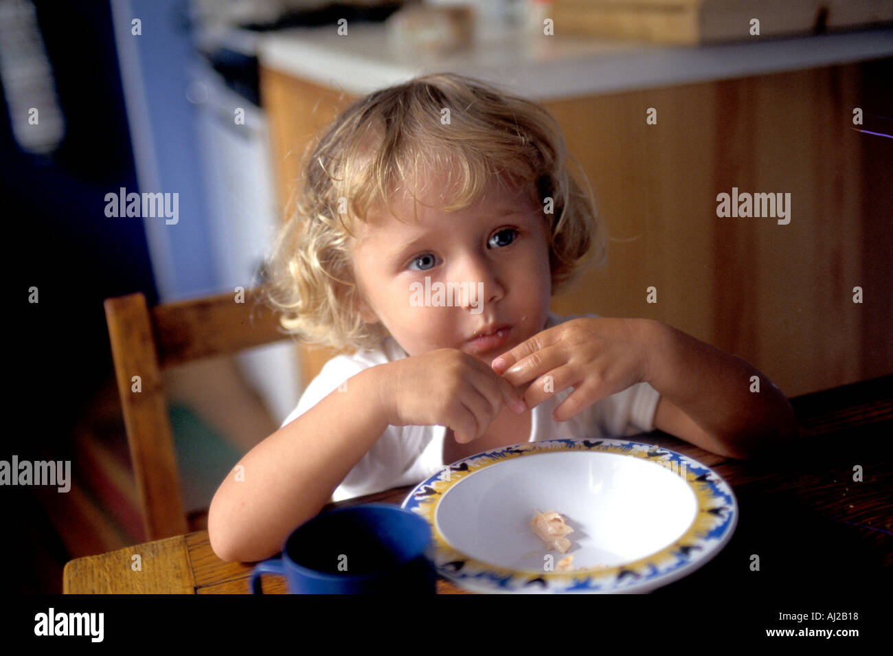 Deux ans, fille de manger son petit-déjeuner à table England UK Banque D'Images