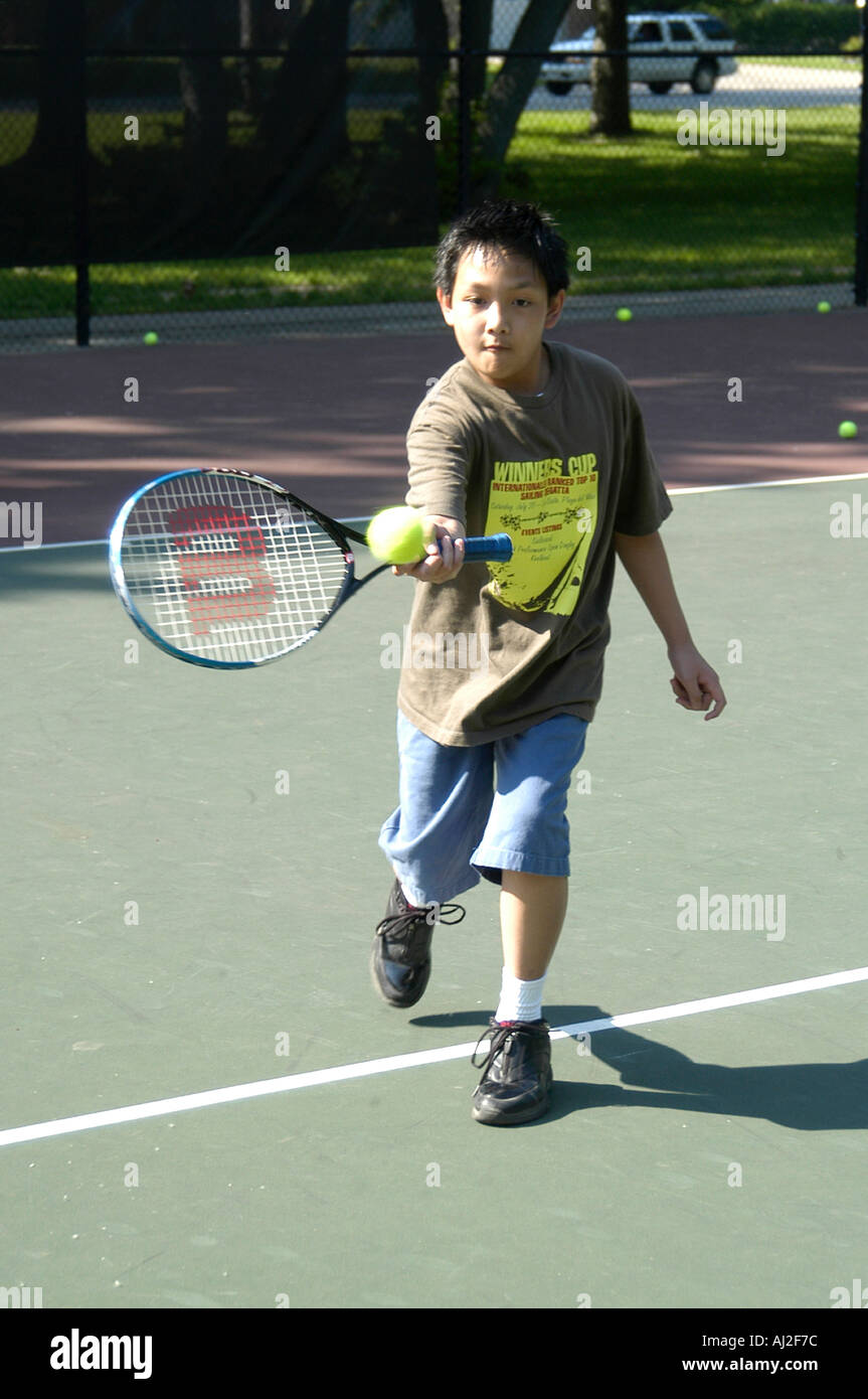 Les enfants apprennent à jouer au tennis à cour de récréation publique Banque D'Images