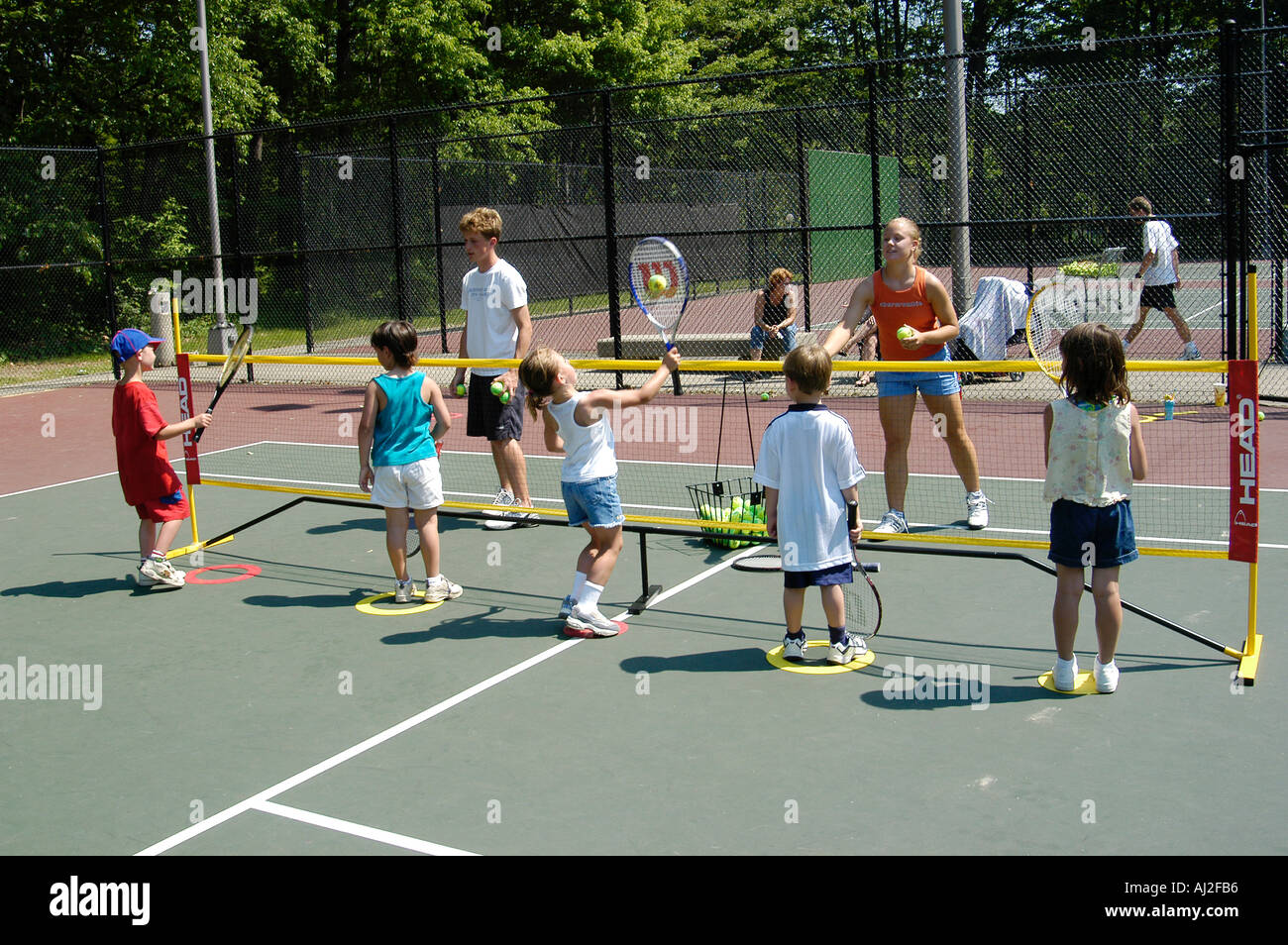 Les enfants apprennent à jouer au tennis à cour de récréation publique Banque D'Images
