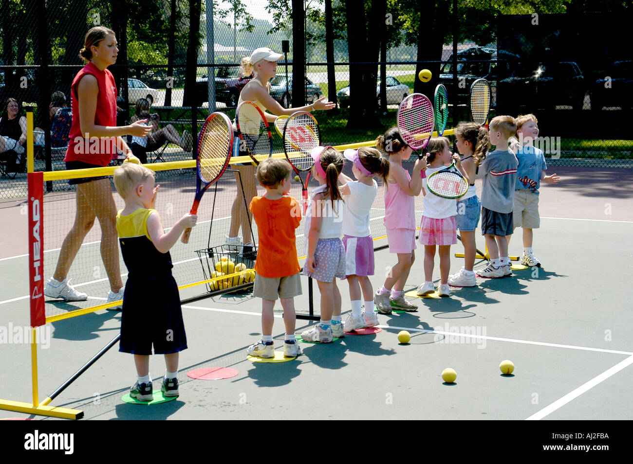 Les enfants apprennent à jouer au tennis à cour de récréation publique Banque D'Images