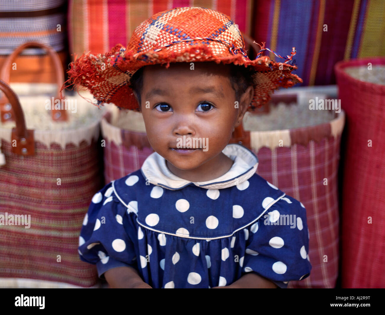 Une jeune fille à côté d'un road-side stall qui est d'offrir à la vente des paniers et des chapeaux en raphia près de Antananarivo Banque D'Images