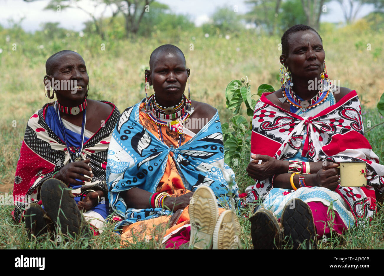 Un portrait de trois maasai en robe traditionnelle, en train de boire du thé lors d'une réunion du groupe coopératif des femmes. Kajiado, Kenya Banque D'Images