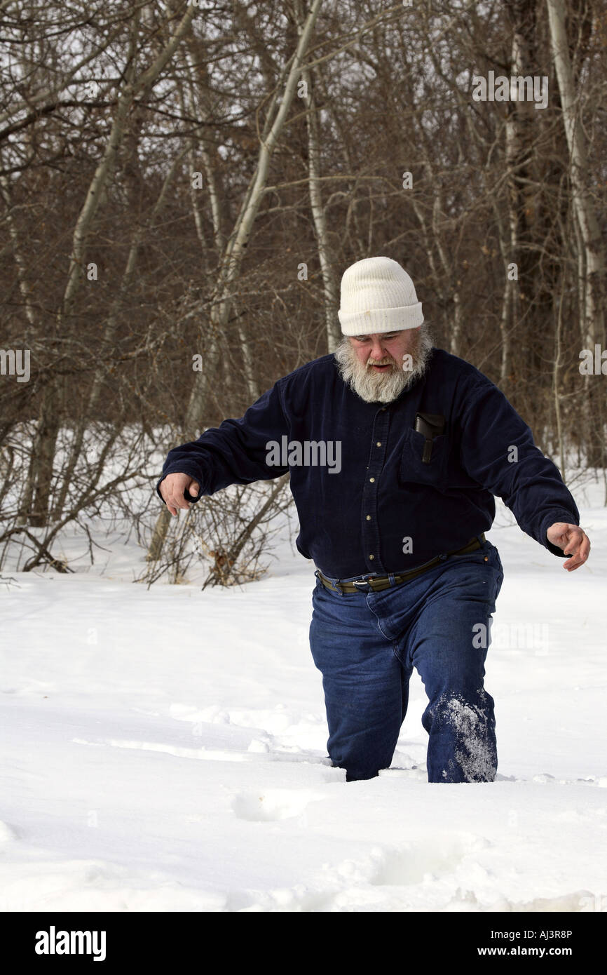 Vieil homme marchant dans la neige profonde Banque D'Images