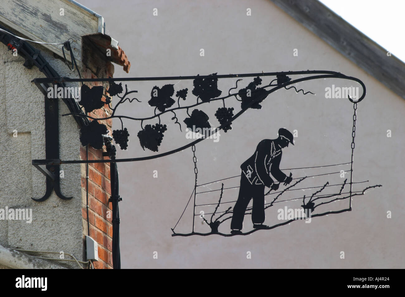 Une enseigne peinte en fer forgé qui illustre le thème de la production de vin et champagne : panneau noir montrant un homme faisant l'élagage Banque D'Images