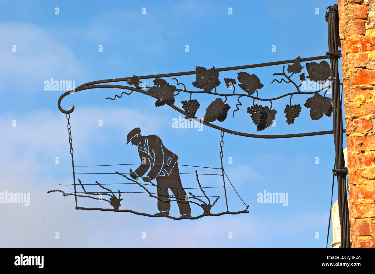 Une enseigne peinte en fer forgé qui illustre le thème de la production de vin et champagne : panneau noir montrant un homme faisant l'élagage Banque D'Images