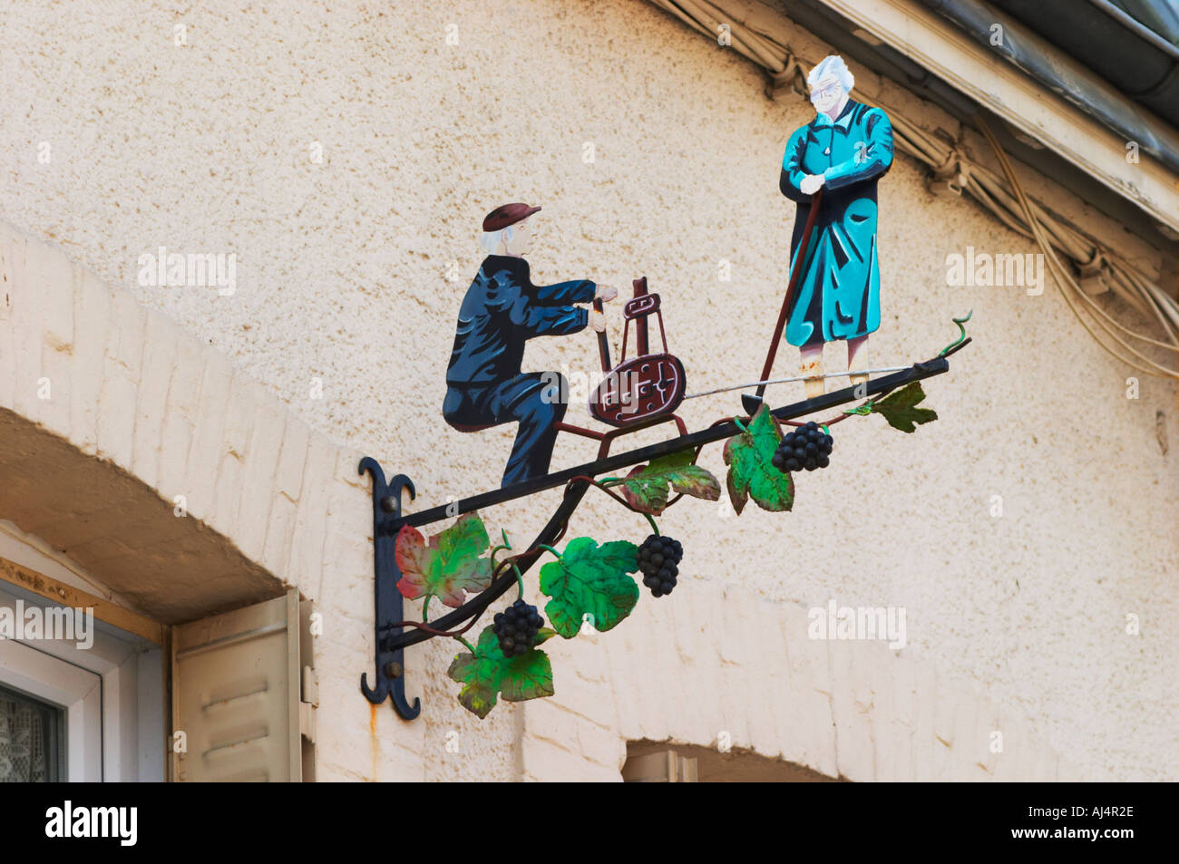 Une enseigne peinte en fer forgé qui illustre le thème de la production de vin et champagne : un homme en assis à une station de remplissage Banque D'Images