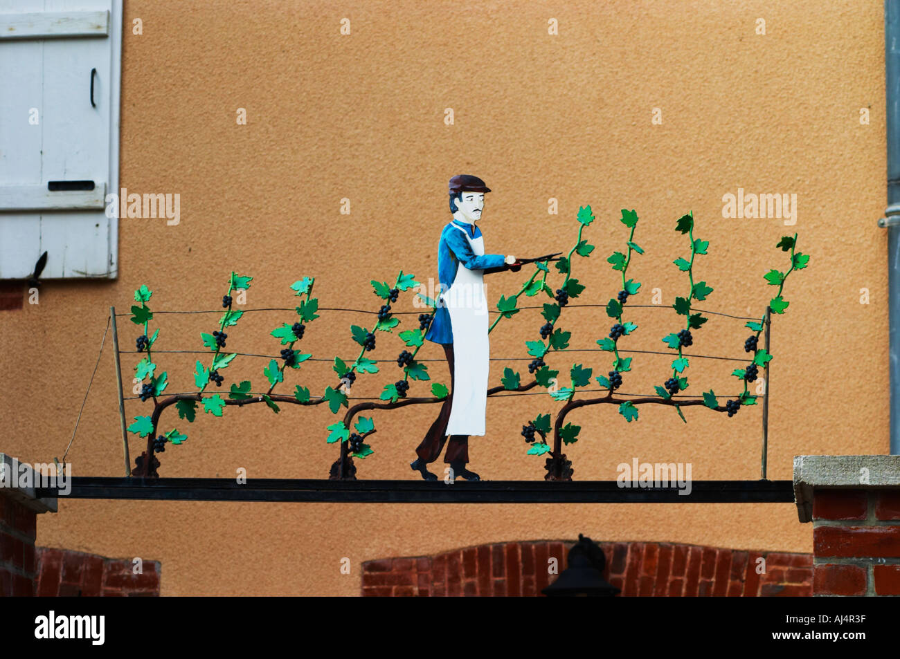 Une enseigne peinte en fer forgé qui illustre le thème de la production de vin et champagne : Un homme taillant la vigne avec des feuilles et des raisins avec un secateur, le village d'Hautvillers dans la vallée de la Marne, Champagne, Marne, Ardennes, France Banque D'Images