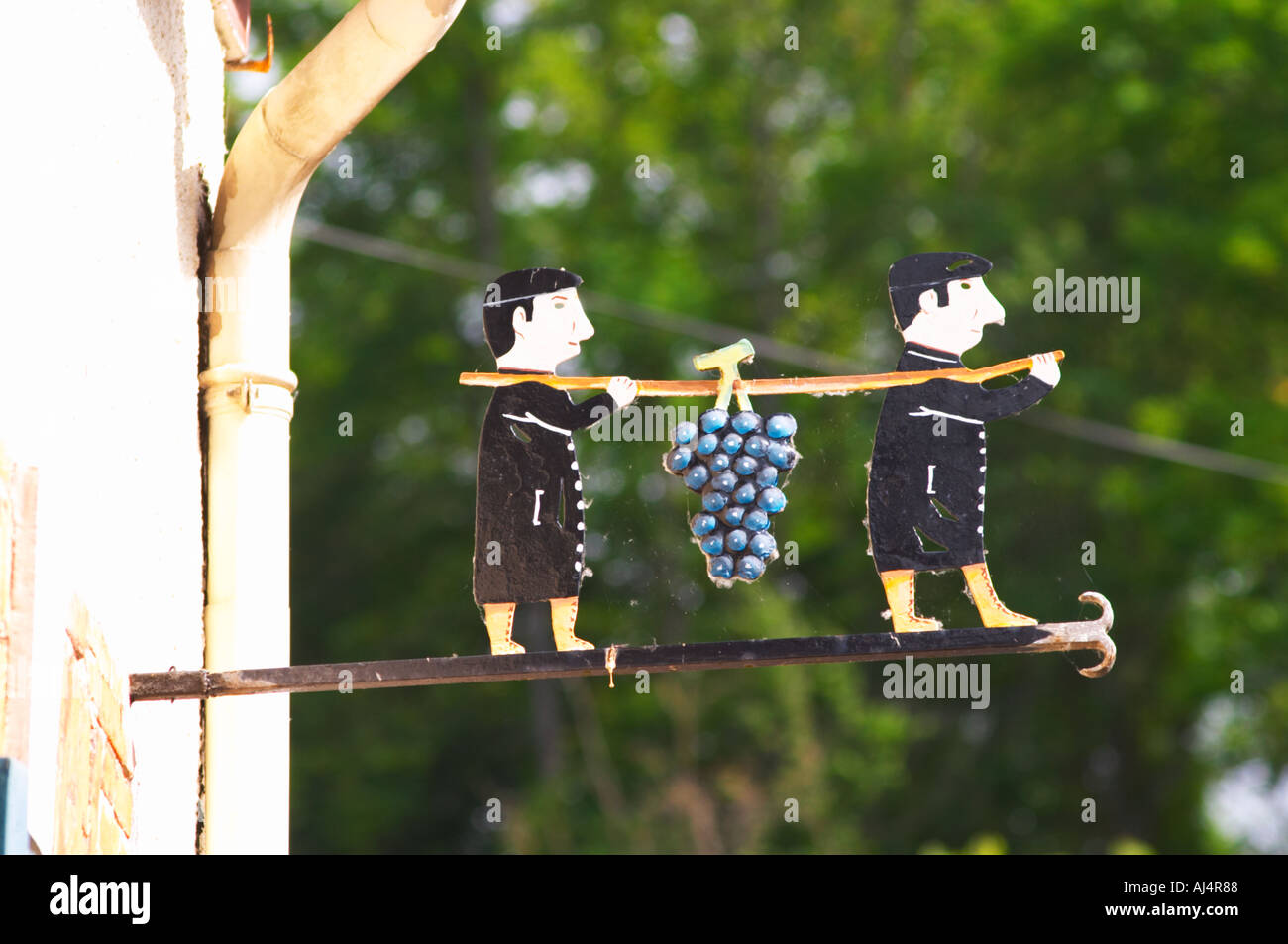 Une enseigne peinte en fer forgé qui illustre le thème de la production de vin et champagne : deux hommes en noir tenant une perche sur le Banque D'Images