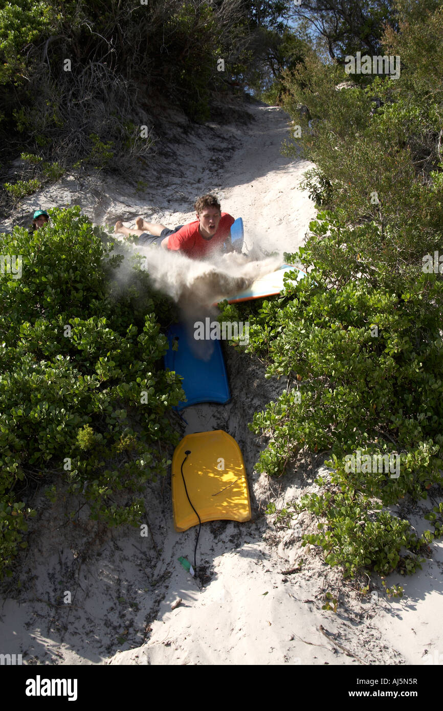 Jeune homme ou garçon surf de sable s'abattre une dune à Yacaaba près de Port Stephens de Hawks Nest NSW Australie Nouvelle-Galles du Sud CC 2D Banque D'Images