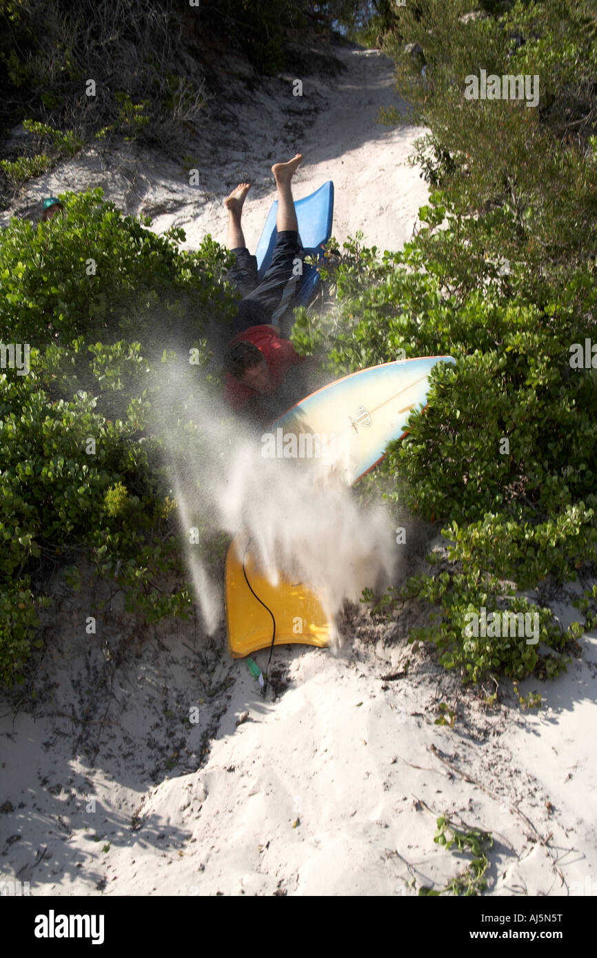 Jeune homme ou garçon surf de sable s'abattre une dune à Yacaaba près de Port Stephens de Hawks Nest NSW Australie Nouvelle-Galles du Sud CC 2E Banque D'Images