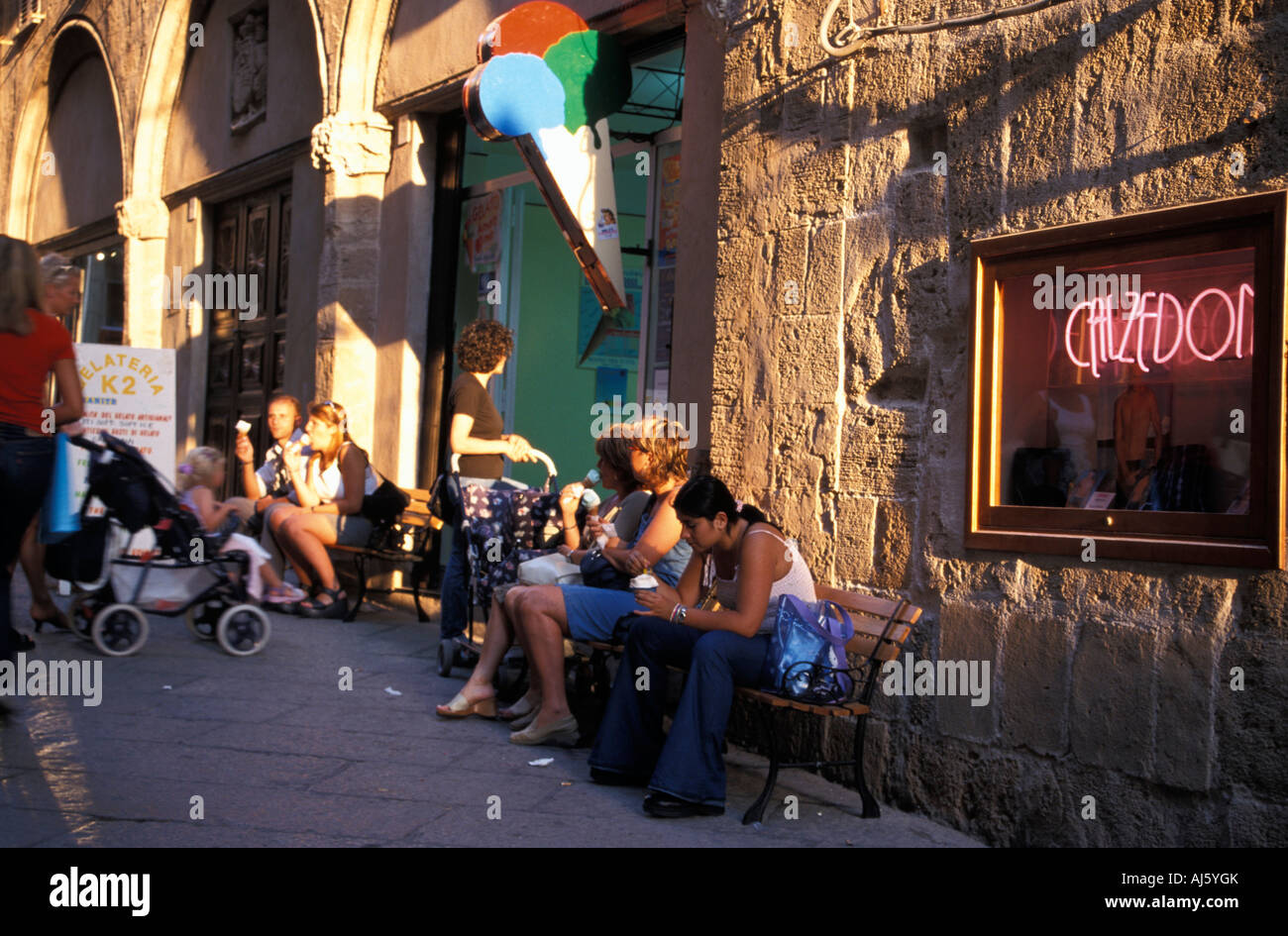 Des gens assis en face d'un glacier et de lécher la crème glacée La vieille ville de Alghero Gallura Sardaigne Italie Banque D'Images