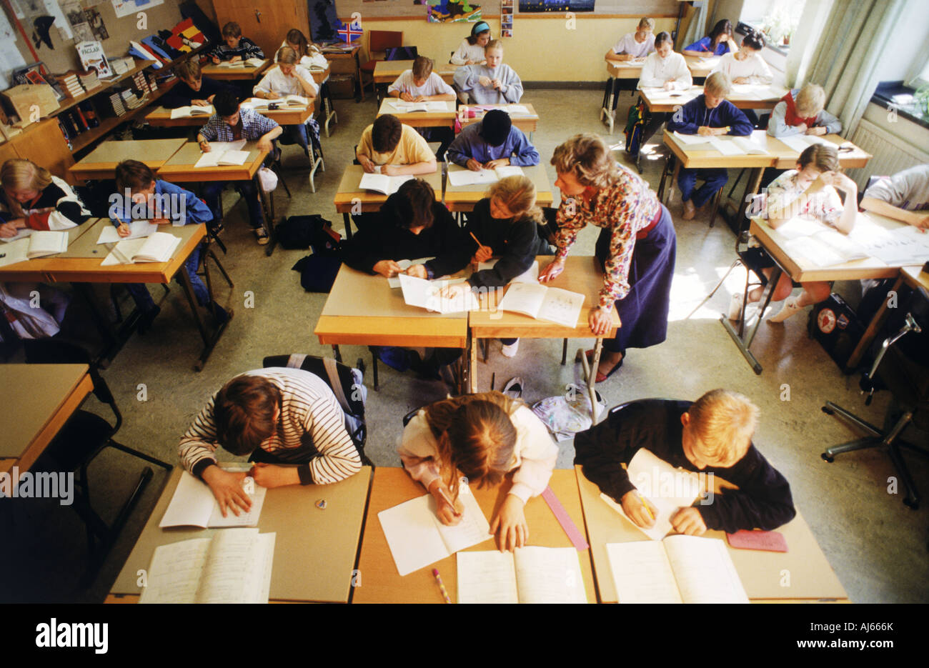 Sommaire des enfants de l'école primaire la lecture et l'écriture à un bureau individuel avec l'enseignant en classe suédois Banque D'Images