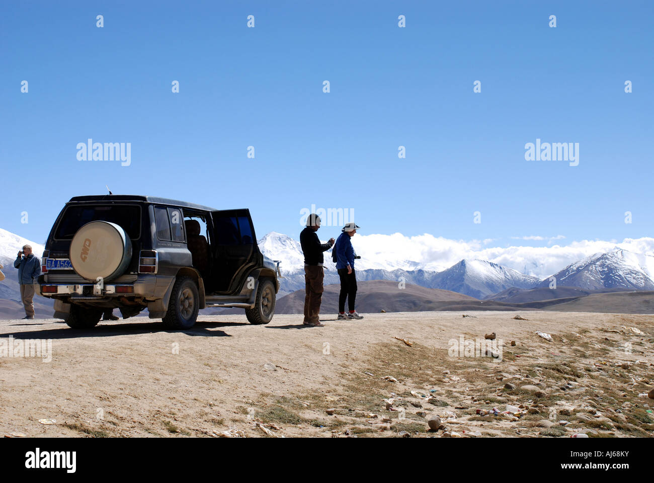 Tibet les cimes enneigées du haut Himalaya sont vus au-dessus des collines arides du plateau tibétain avec un touriste Land cruiser Banque D'Images